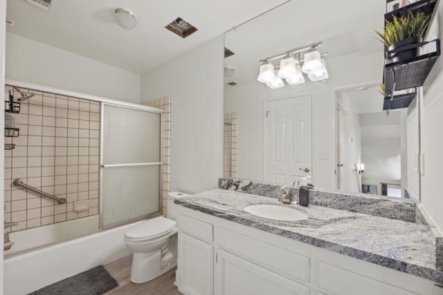 full bathroom featuring toilet, combined bath / shower with glass door, vanity, and wood-type flooring