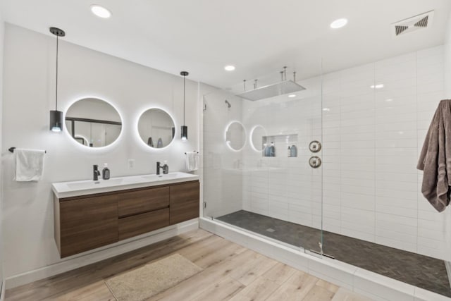 bathroom with vanity, tiled shower, and wood-type flooring