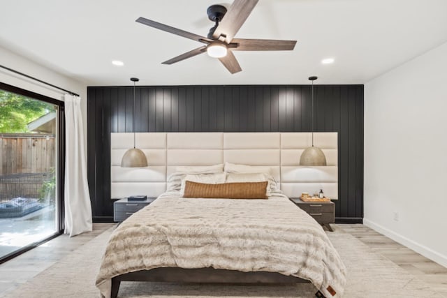 bedroom featuring light hardwood / wood-style flooring, wood walls, access to exterior, and ceiling fan