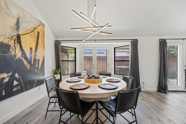 dining area with an inviting chandelier, light hardwood / wood-style flooring, french doors, and a healthy amount of sunlight