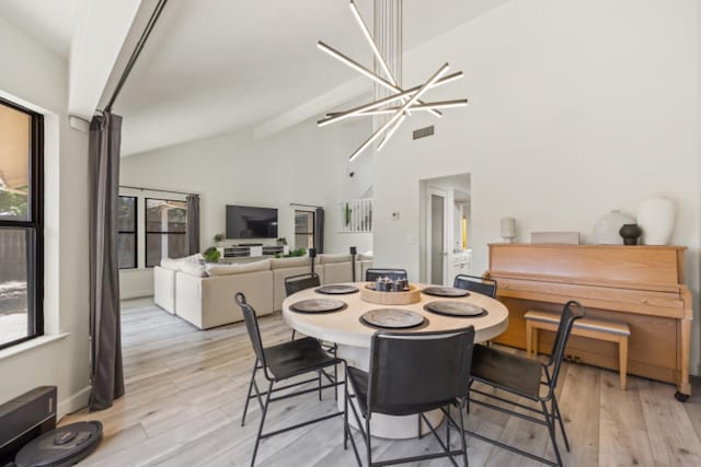 dining room featuring light hardwood / wood-style floors, high vaulted ceiling, and a chandelier