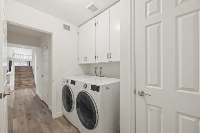 laundry room with cabinets, washer and dryer, and light hardwood / wood-style floors