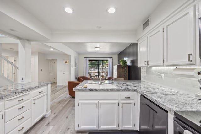 kitchen featuring light hardwood / wood-style flooring, kitchen peninsula, white cabinets, and sink