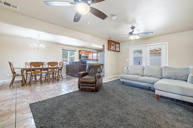 living room featuring light tile patterned floors, ceiling fan with notable chandelier, and french doors