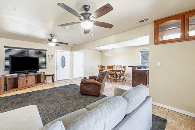 living room with ceiling fan with notable chandelier and light tile patterned floors