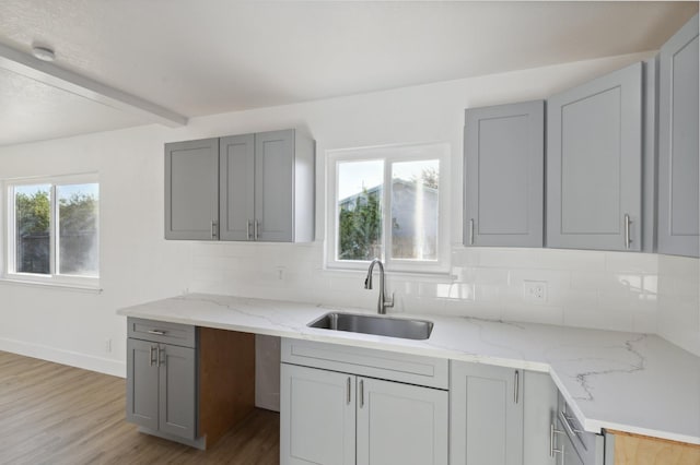 kitchen with light wood-type flooring, sink, and a healthy amount of sunlight