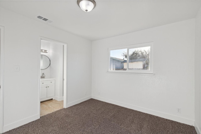 unfurnished bedroom with light colored carpet, ensuite bath, and sink