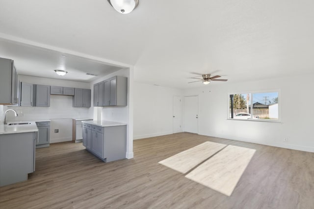 kitchen with ceiling fan, gray cabinetry, sink, and light wood-type flooring