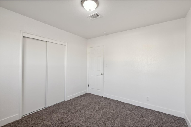 unfurnished bedroom featuring dark colored carpet and a closet