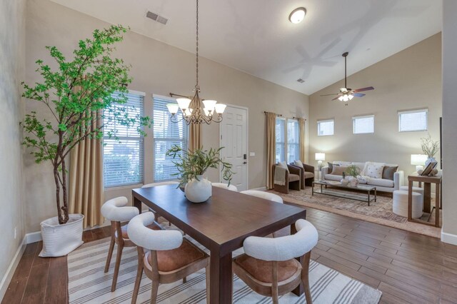 dining area with high vaulted ceiling, ceiling fan with notable chandelier, and dark hardwood / wood-style flooring