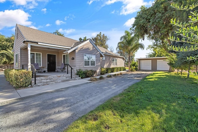 view of front of property with a garage, a front lawn, and an outbuilding