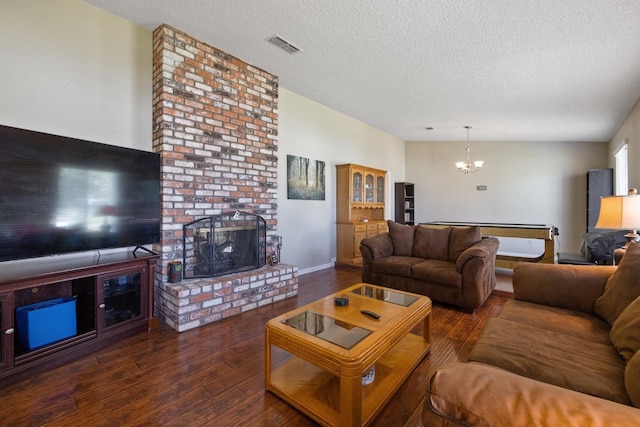 living room featuring a fireplace, a textured ceiling, lofted ceiling, dark hardwood / wood-style floors, and a notable chandelier