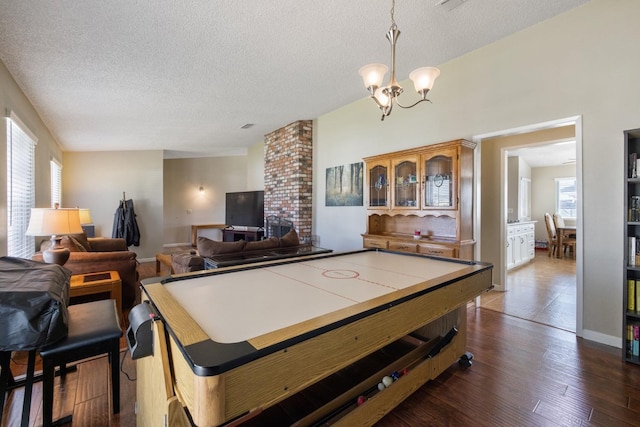 playroom with a notable chandelier, dark hardwood / wood-style floors, and a textured ceiling