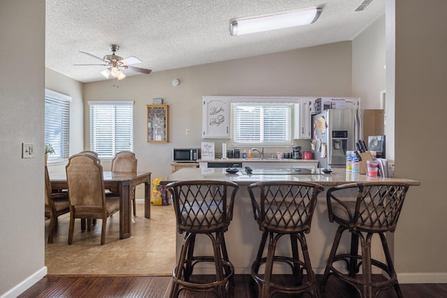 kitchen with appliances with stainless steel finishes, hardwood / wood-style floors, ceiling fan, and a wealth of natural light