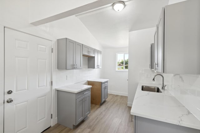 kitchen featuring light wood-type flooring, backsplash, sink, gray cabinets, and lofted ceiling