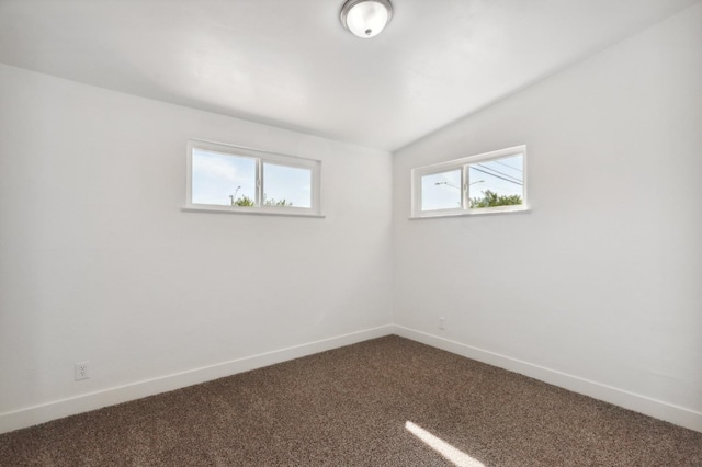 carpeted empty room with vaulted ceiling