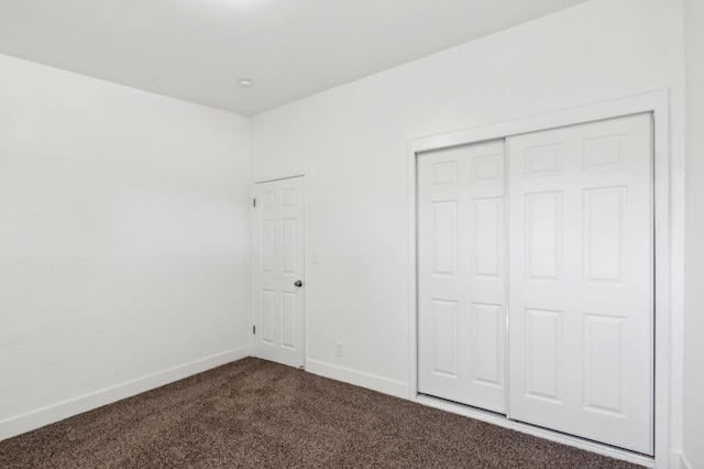 unfurnished bedroom featuring dark carpet and a closet