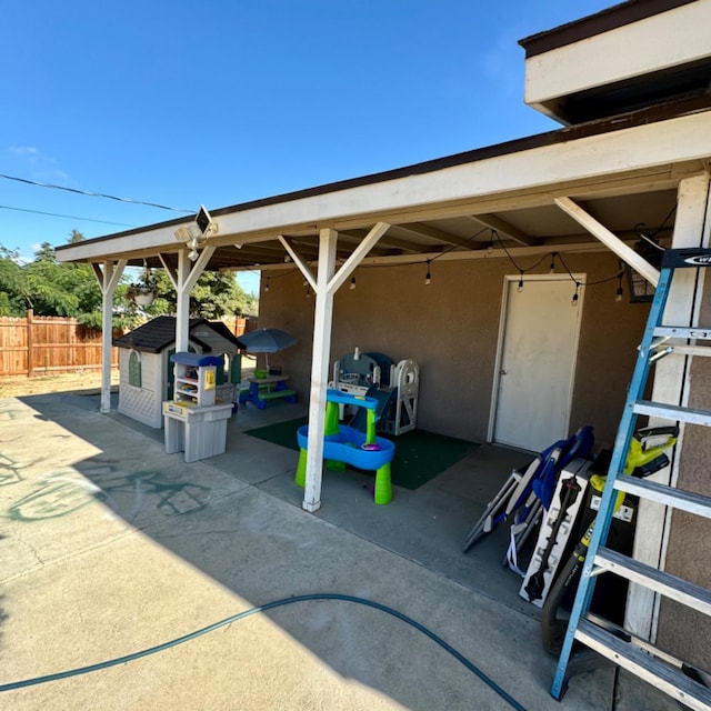 view of patio / terrace with an outdoor structure, a storage unit, and fence