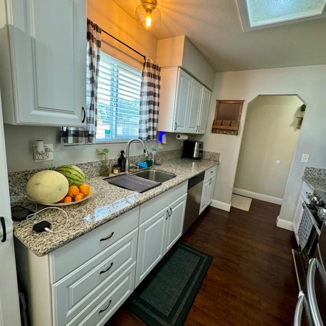 kitchen featuring stainless steel appliances, a sink, baseboards, white cabinets, and dark wood-style floors