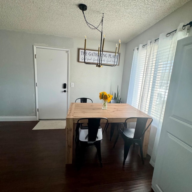 dining room with dark wood-style flooring, a textured ceiling, and baseboards