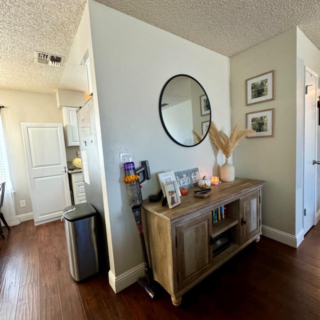 hallway with a textured ceiling, dark wood finished floors, and baseboards