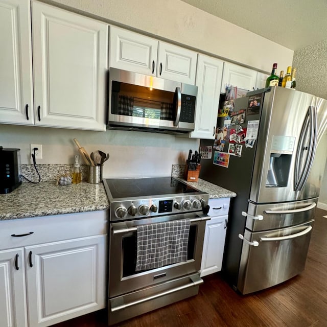 kitchen featuring white cabinetry, appliances with stainless steel finishes, dark wood finished floors, and light stone counters