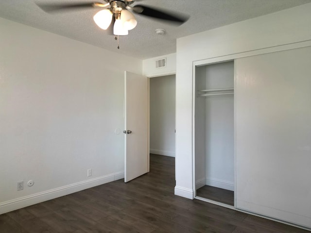 unfurnished bedroom featuring a closet, ceiling fan, dark hardwood / wood-style floors, and a textured ceiling