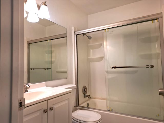 full bathroom featuring enclosed tub / shower combo, vanity, and toilet