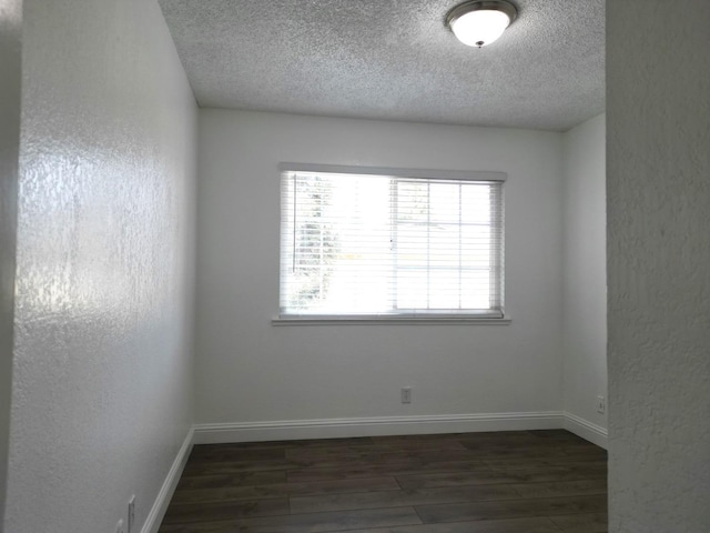 unfurnished room featuring a textured ceiling and dark hardwood / wood-style floors