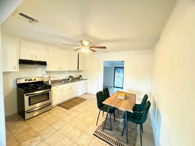 kitchen featuring ceiling fan, sink, light tile patterned floors, stainless steel range oven, and white cabinets