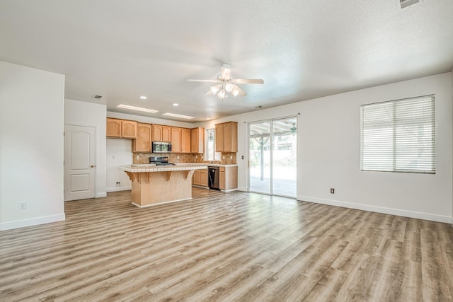 kitchen with appliances with stainless steel finishes, a center island, light hardwood / wood-style floors, ceiling fan, and a breakfast bar area