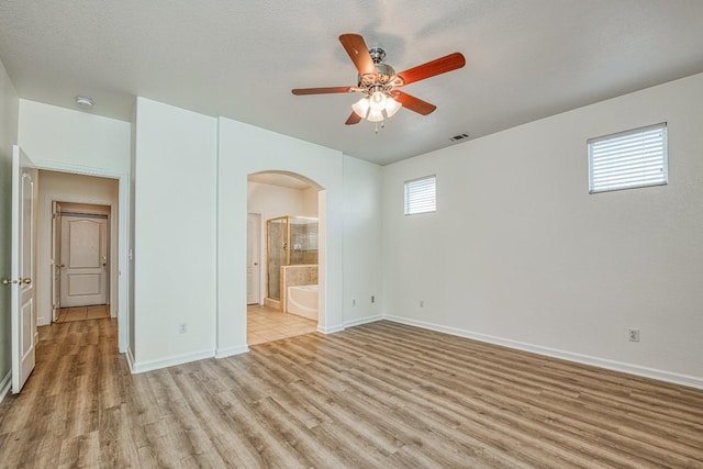 spare room with a textured ceiling, light wood-type flooring, and ceiling fan