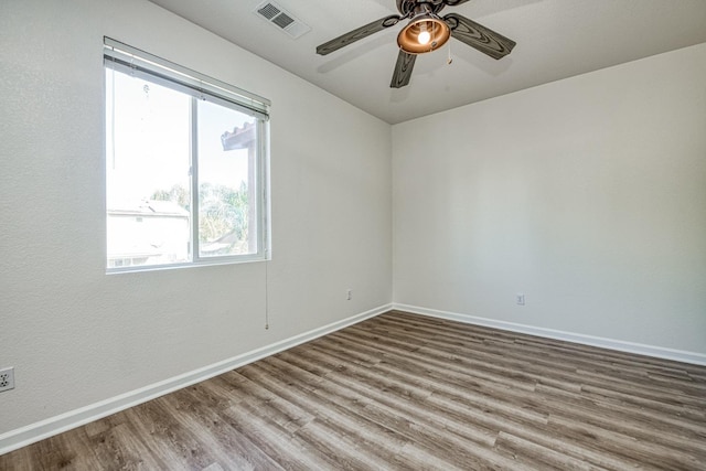 empty room with ceiling fan, a healthy amount of sunlight, and wood-type flooring