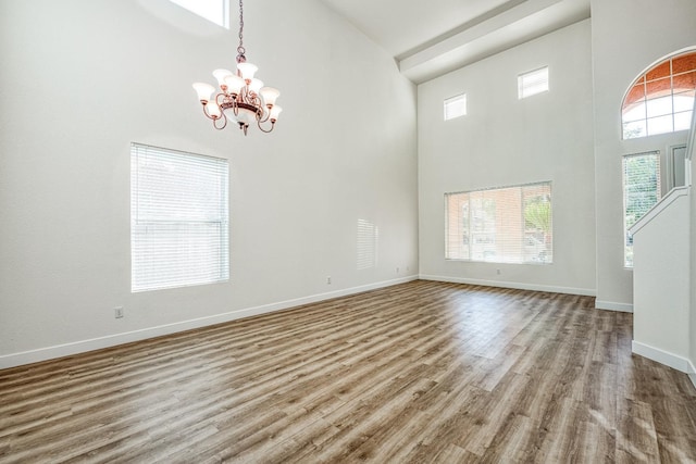 interior space featuring a towering ceiling, a notable chandelier, and hardwood / wood-style flooring