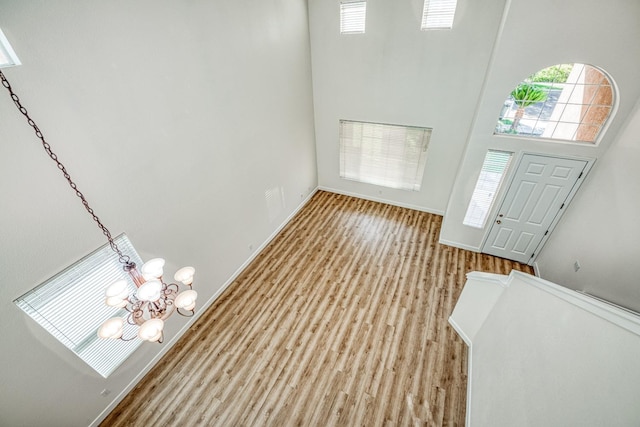 foyer with light hardwood / wood-style flooring, a notable chandelier, and a high ceiling