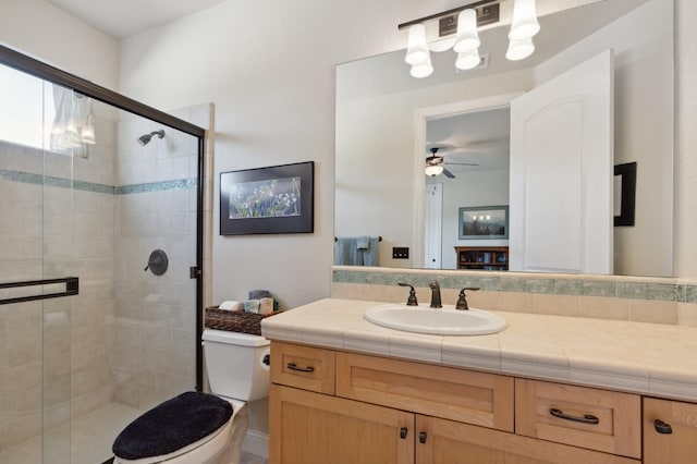 bathroom featuring ceiling fan, a shower with door, vanity, and toilet