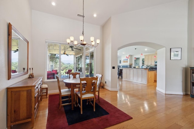 dining room featuring a high ceiling, light hardwood / wood-style flooring, and a notable chandelier