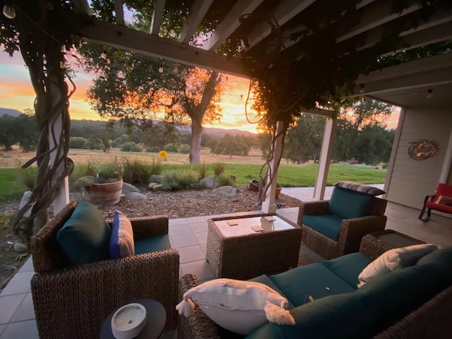 patio terrace at dusk featuring a lawn and an outdoor living space