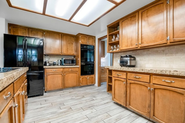 kitchen featuring light wood-type flooring, black appliances, and backsplash