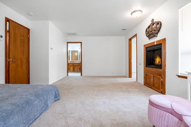 bedroom featuring light colored carpet and ensuite bathroom