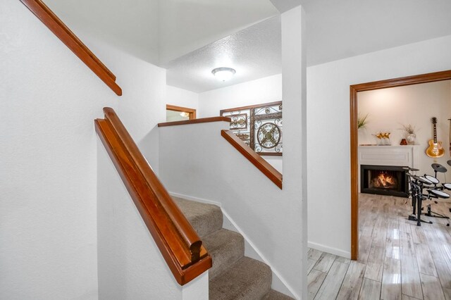 stairway featuring a textured ceiling and hardwood / wood-style floors