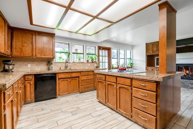 kitchen featuring decorative backsplash, light hardwood / wood-style floors, kitchen peninsula, black appliances, and sink