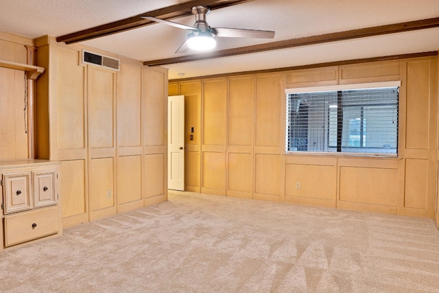 unfurnished room featuring light carpet, ceiling fan, beamed ceiling, and a textured ceiling