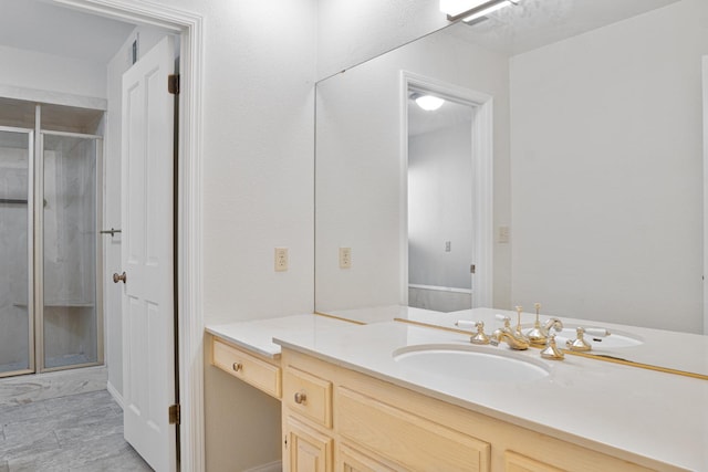 bathroom featuring a shower with door and vanity