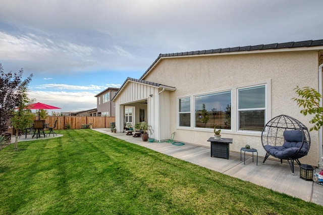 back of house with a patio and a lawn