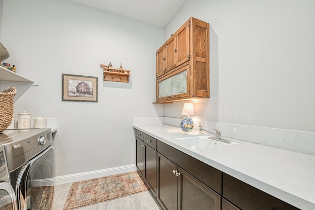 clothes washing area with sink, washer and clothes dryer, light hardwood / wood-style flooring, and cabinets