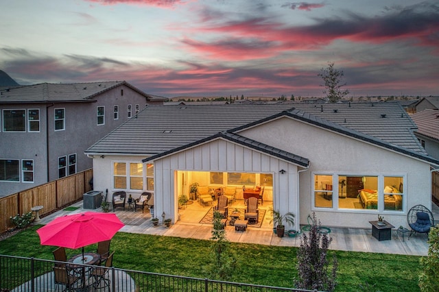 back house at dusk with a patio area and a yard