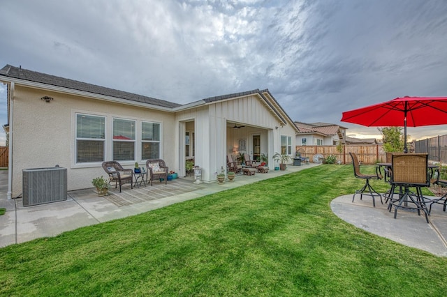 rear view of house with cooling unit, a patio area, a lawn, and ceiling fan