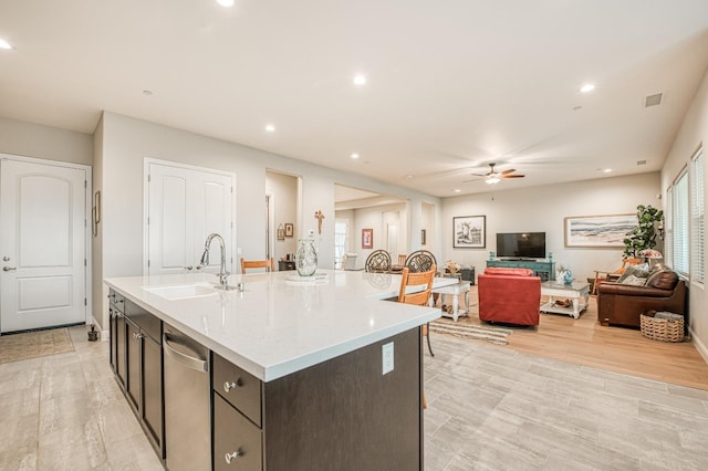 kitchen featuring a center island with sink, sink, dark brown cabinetry, light wood-type flooring, and ceiling fan