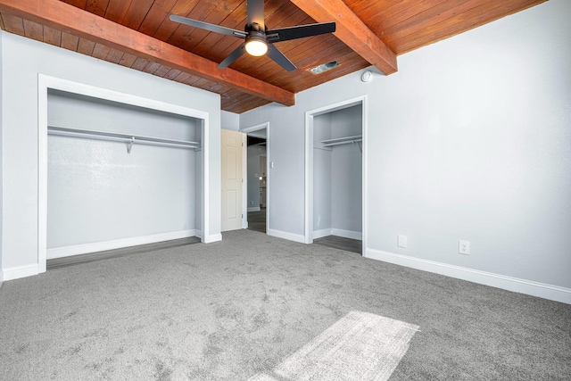 unfurnished bedroom featuring ceiling fan, beamed ceiling, wooden ceiling, and carpet flooring